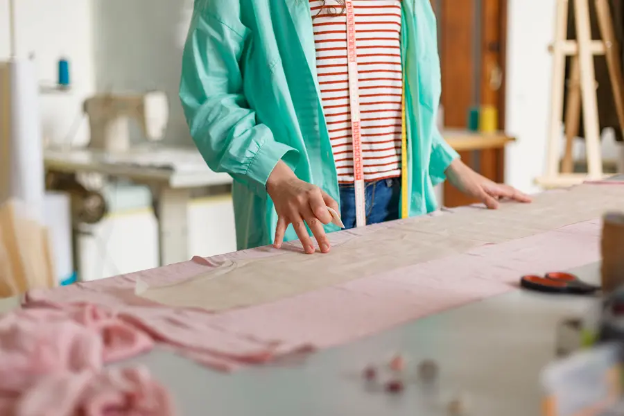 Mujer trabajando en una fábrica textil en Santiago rodeada de telas durante el proceso de confección